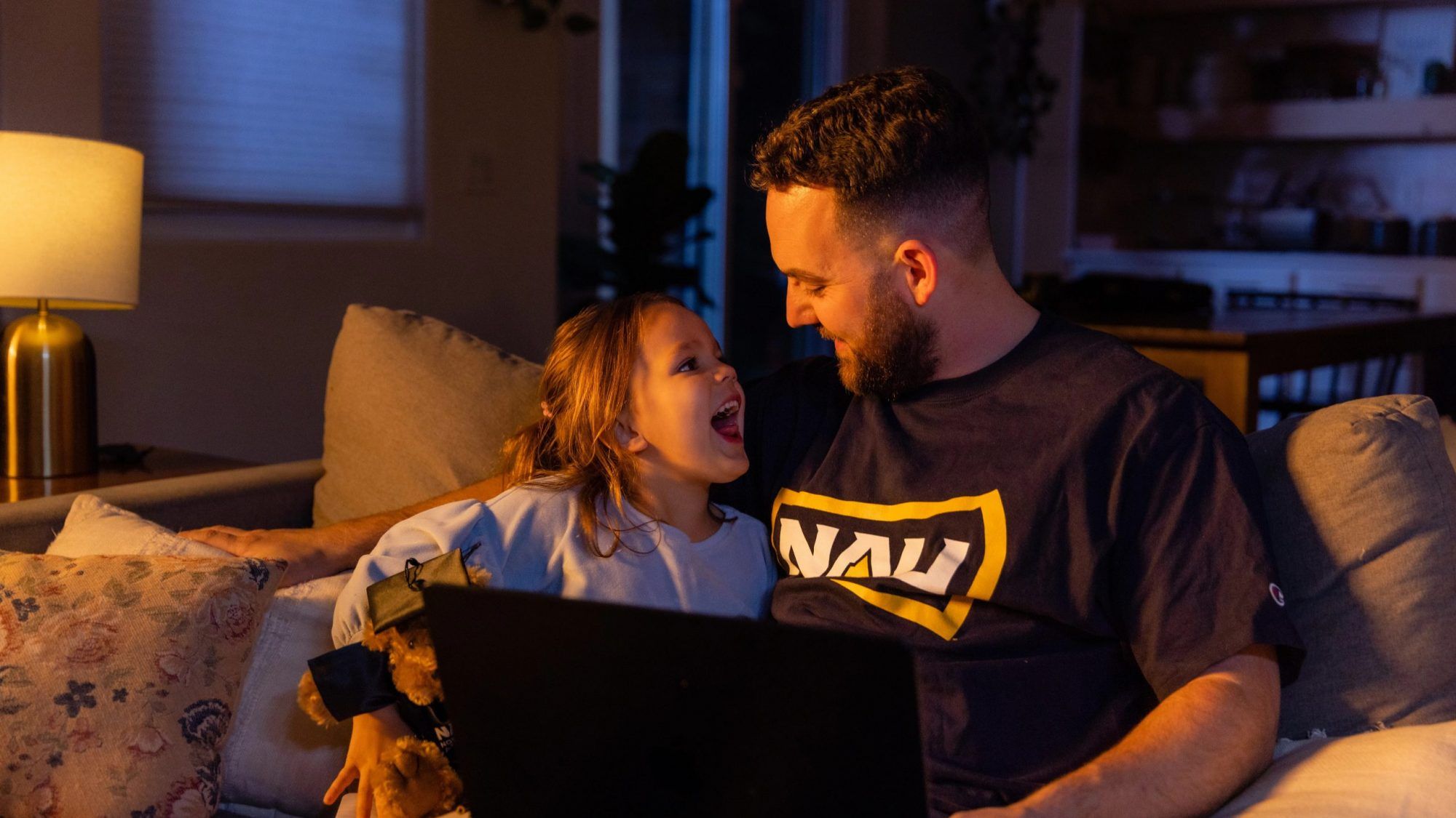 NAU online student works on homework on the couch with his daughter.