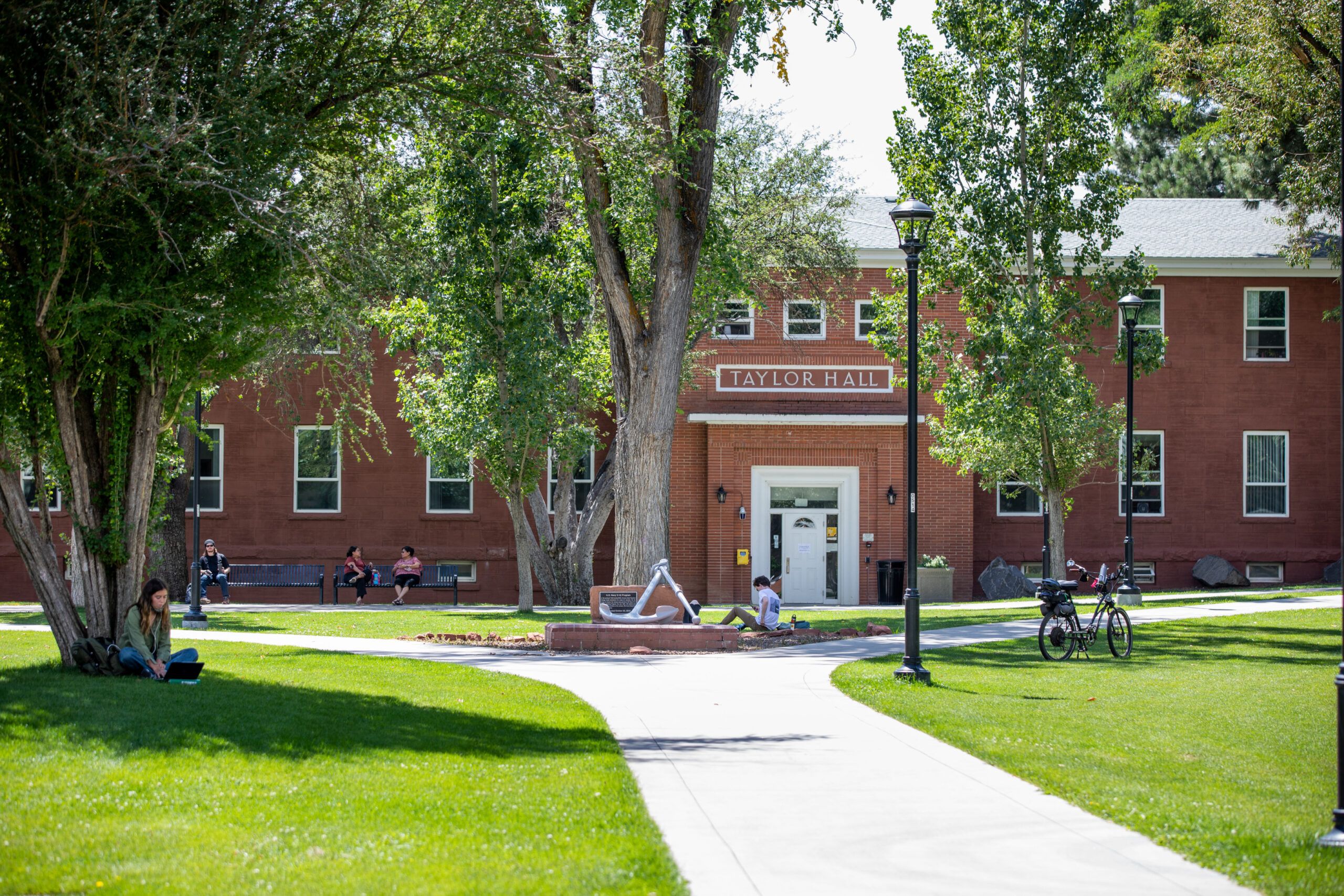 Students sit on the grass outside of Taylor Hall, a residential space, on North Campus at NAU.