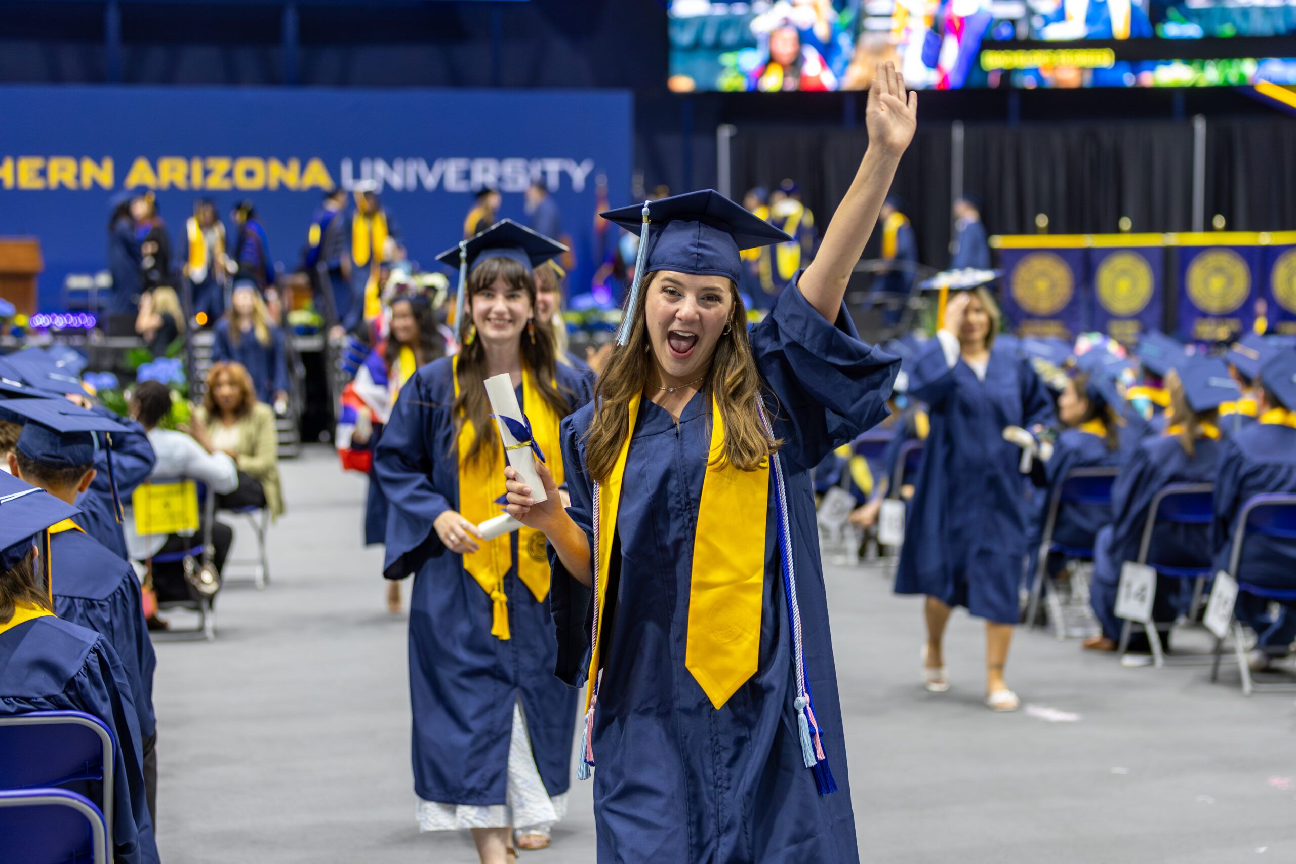 An NAU graduate student smiles and celebrates with her diploma during commencement.