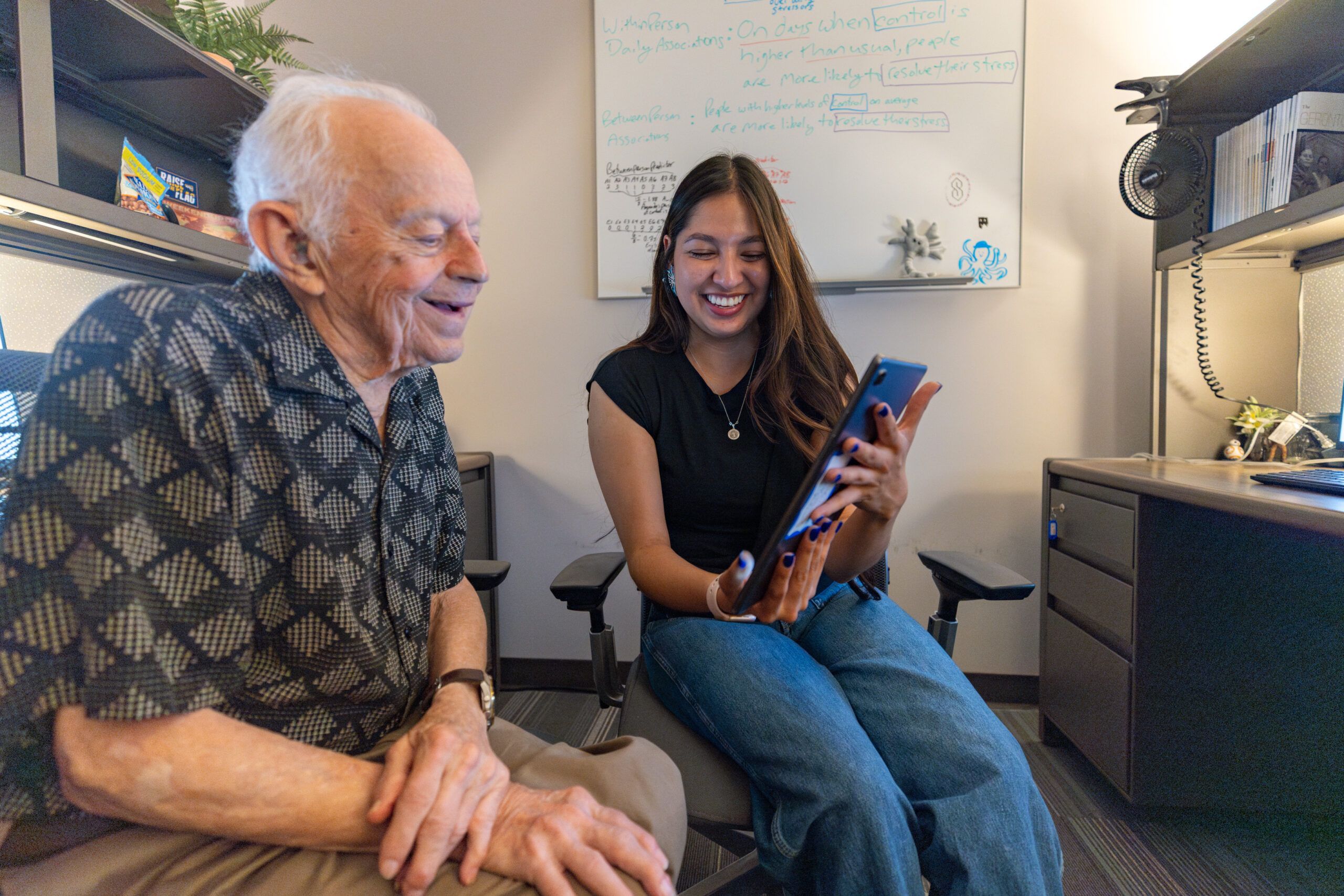 NAU psychology student shows an older individual information on her phone.