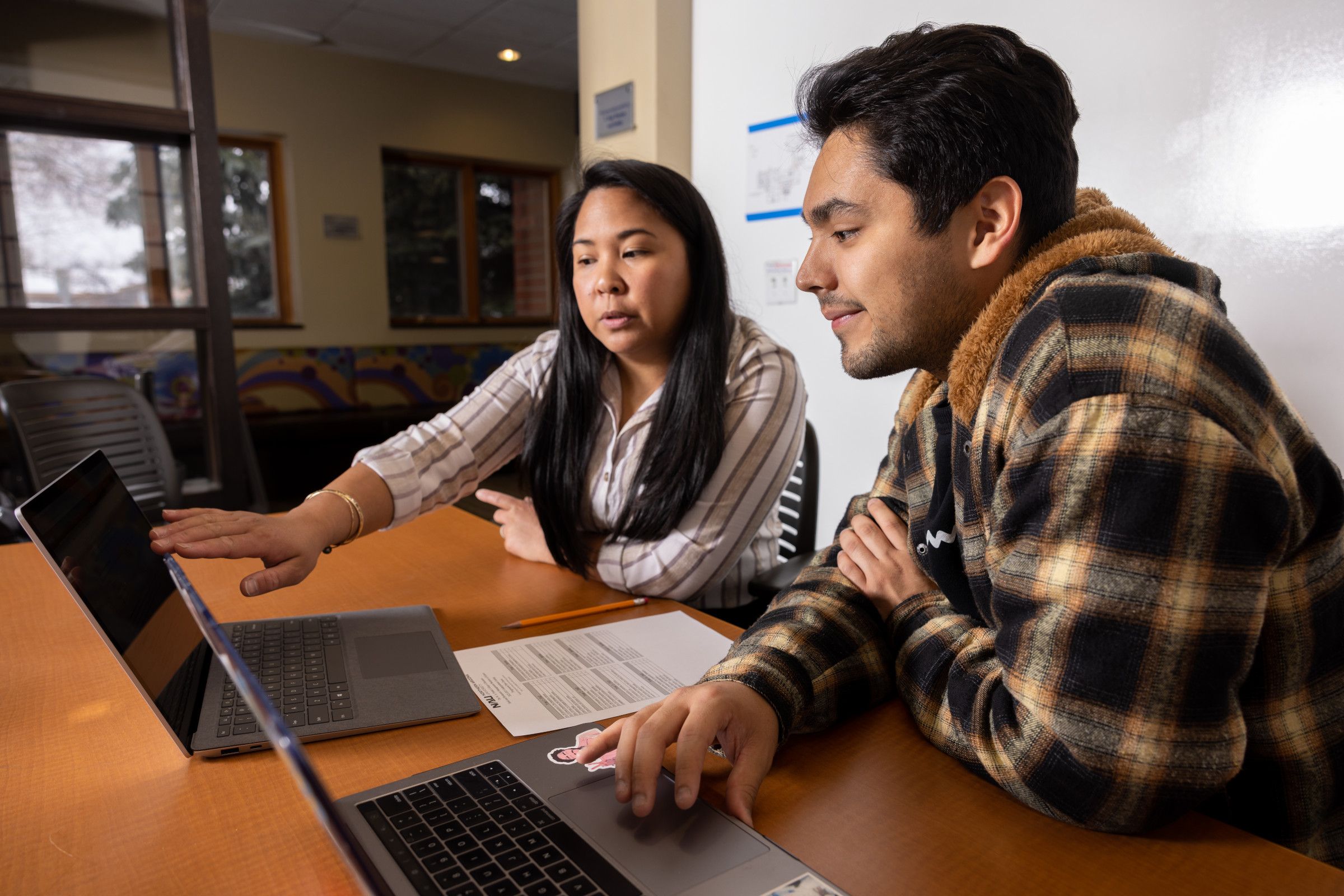 Adviser talking to a student and sharing information on a laptop.