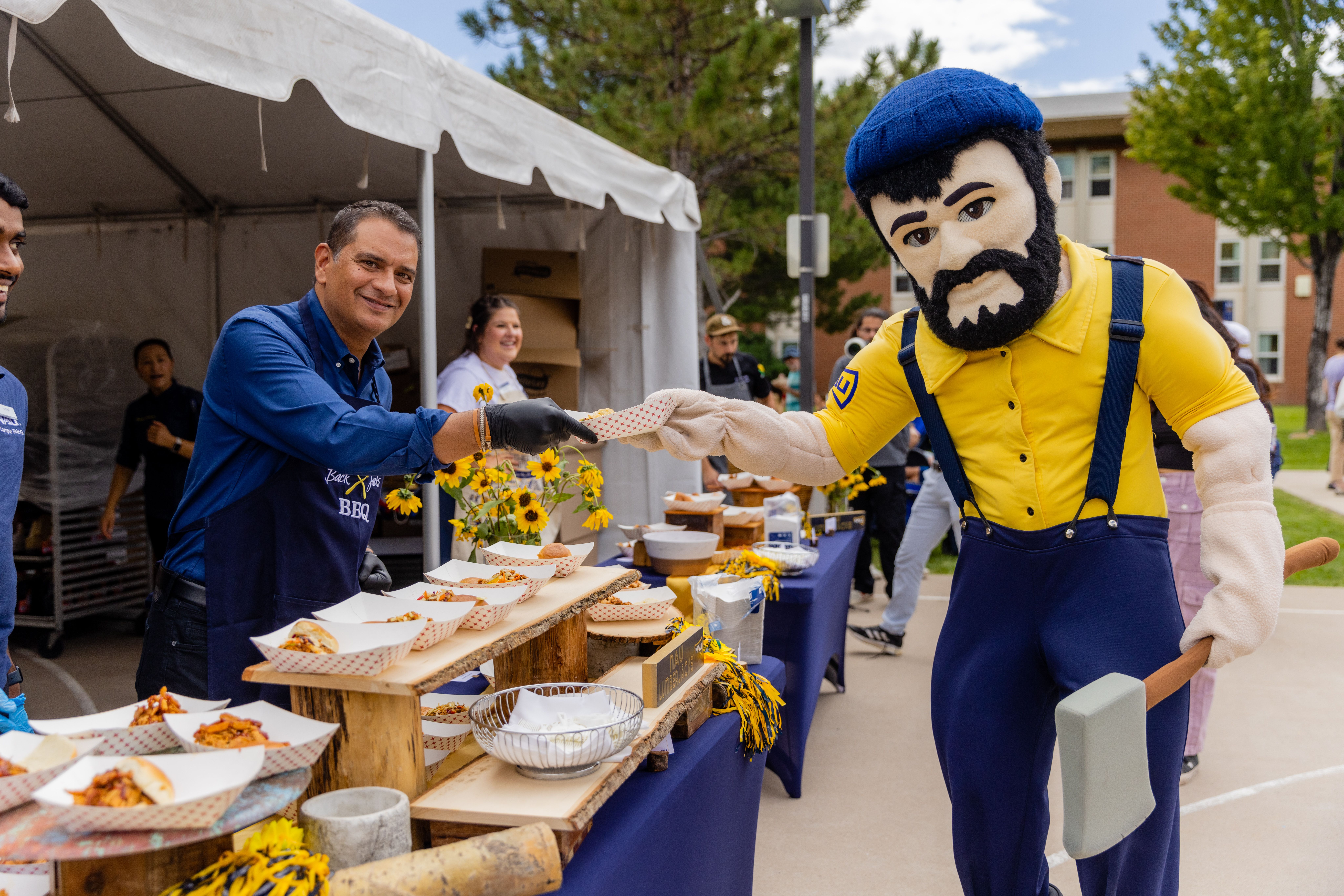 NAU President, Dr. José Luis Cruz Rivera, serving food to NAU's mascot, Louie the Lumberjack.