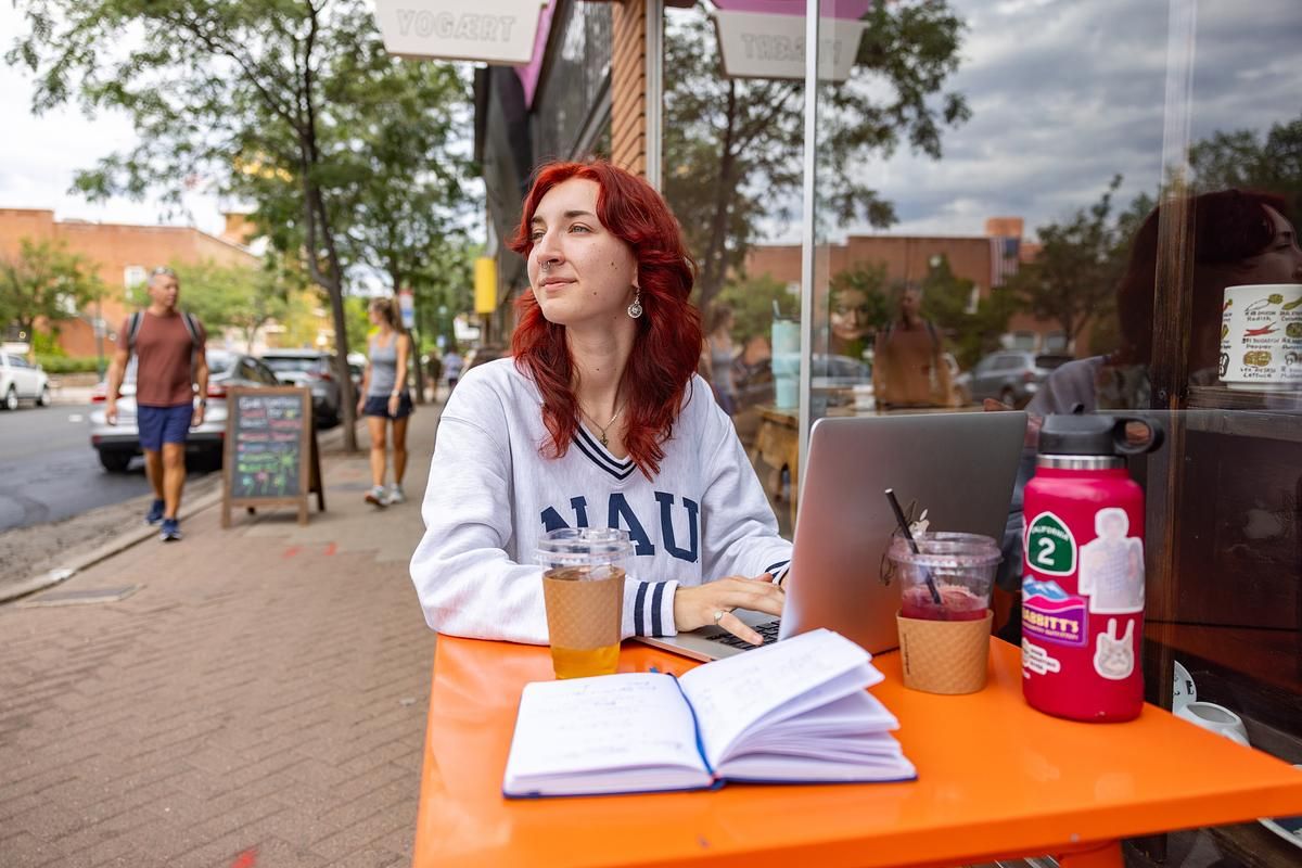 A student works on a laptop and writes in a journal in Downtown Flagstaff.