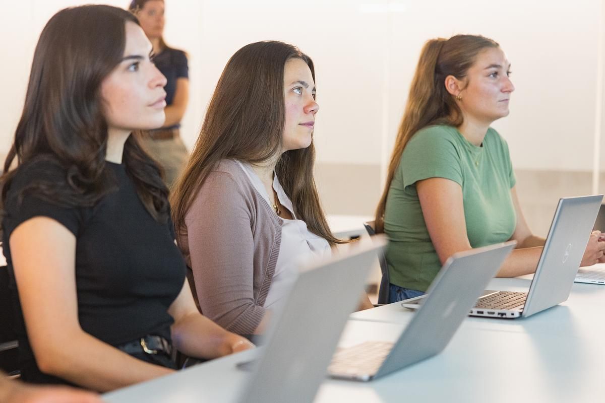 Three students listen in class with their laptops.