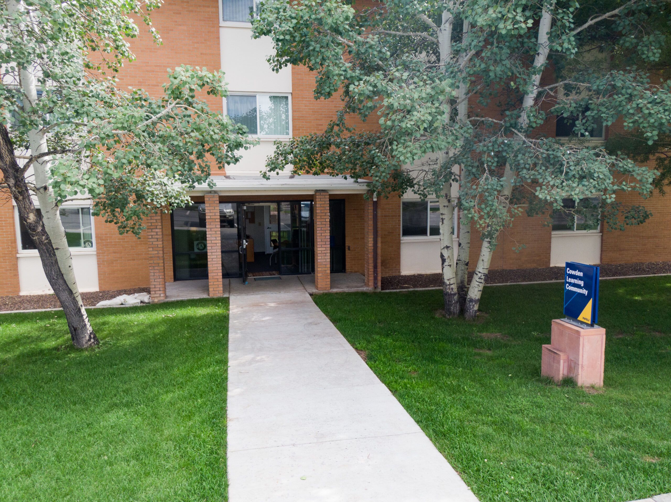 The exterior of Cowden Hall, a residential space and learning center, surrounded by trees on Flagstaff campus.