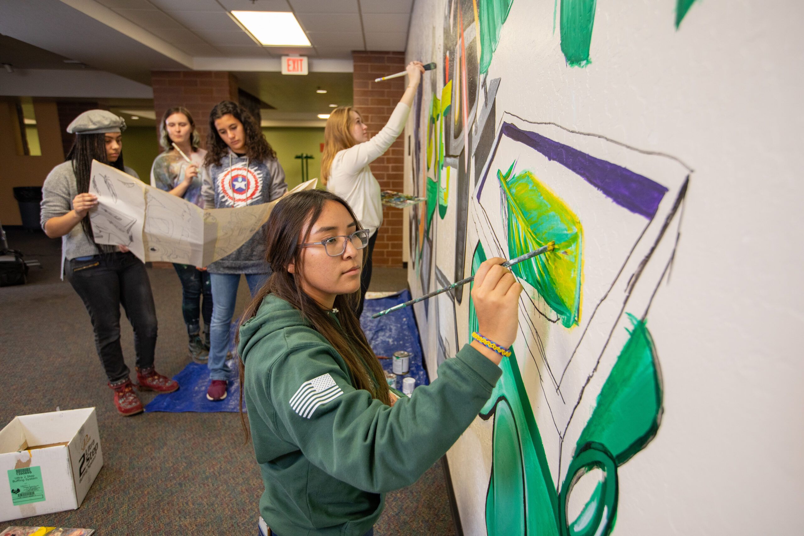 An NAU art student carefully applies paint to an inside mural.
