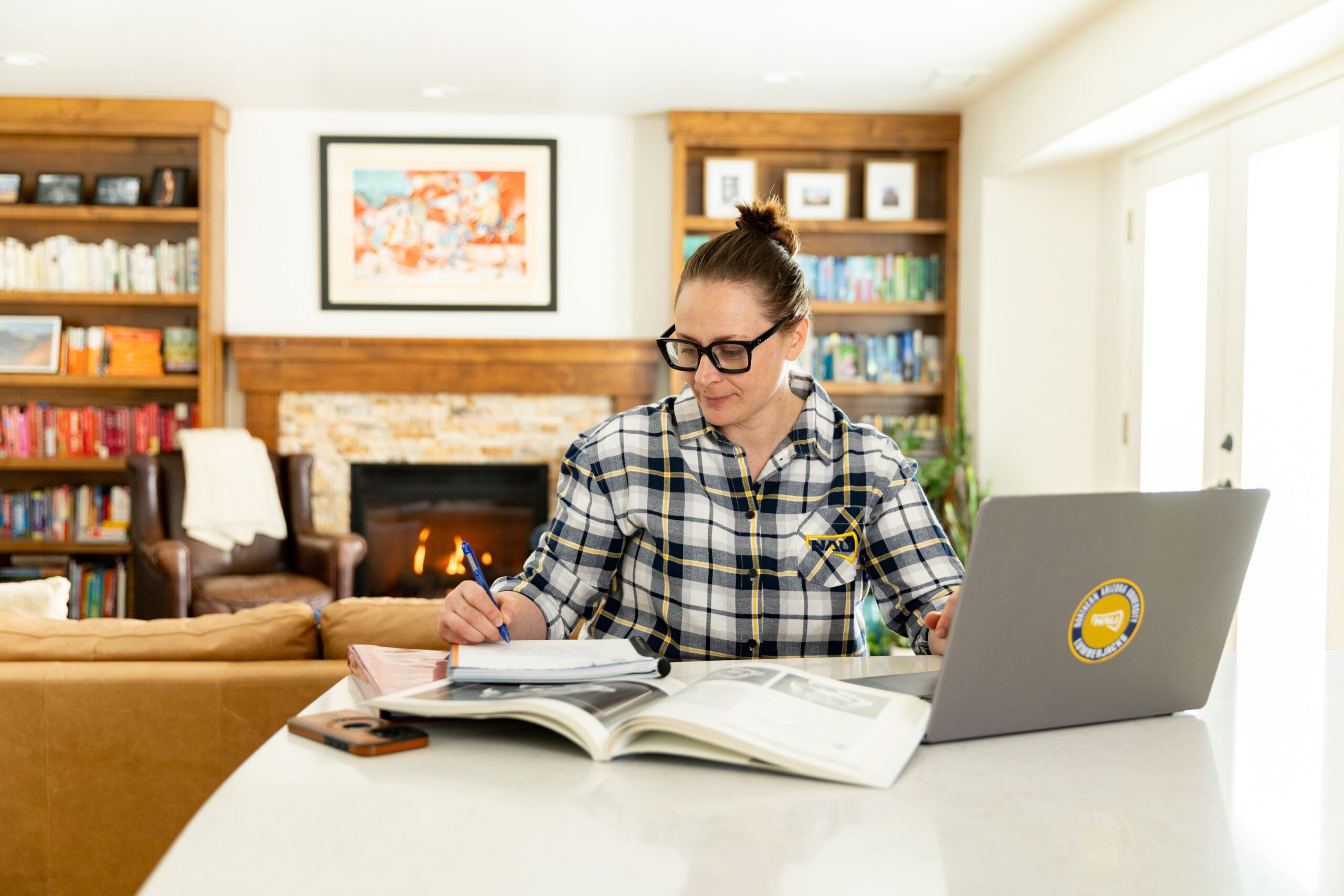 NAU student writing on a notepad while working on a laptop indoors.