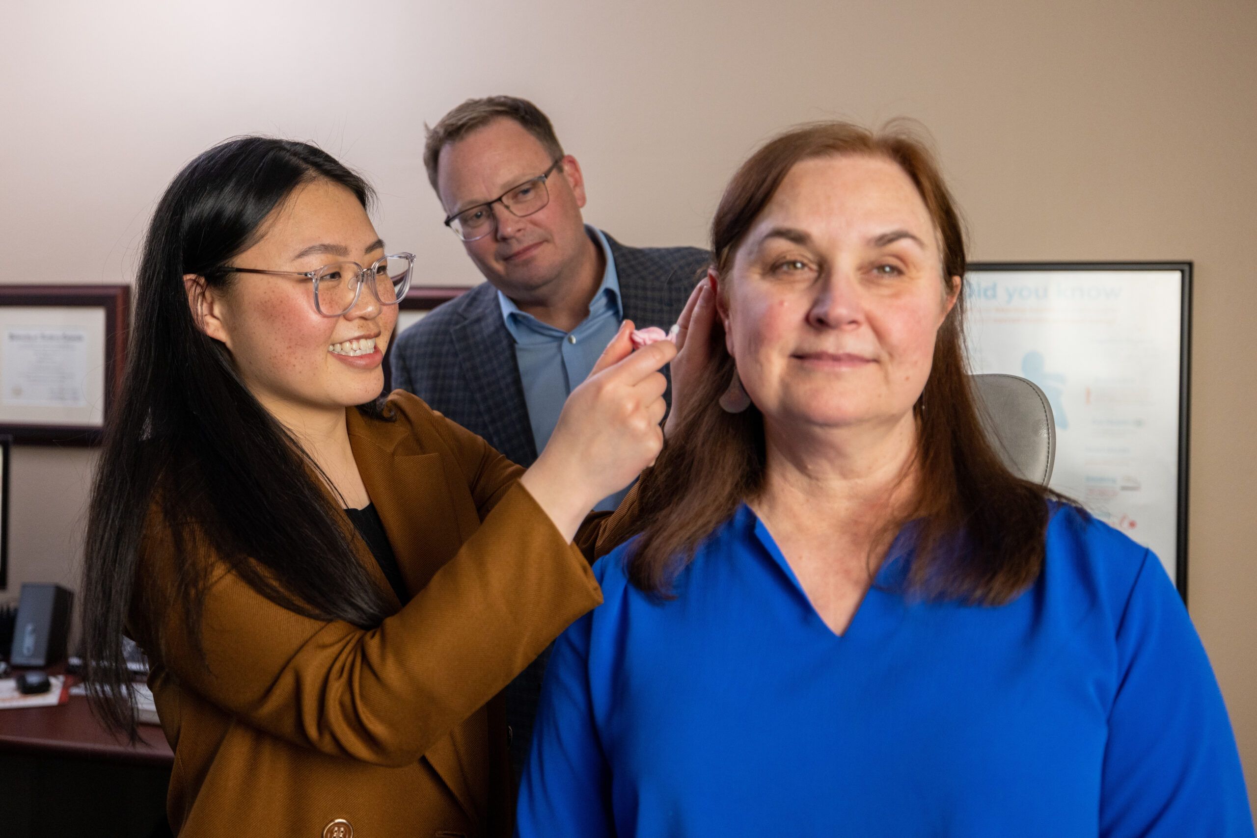 An NAU Health Sciences student practices assisting a hearing aid on a patient.