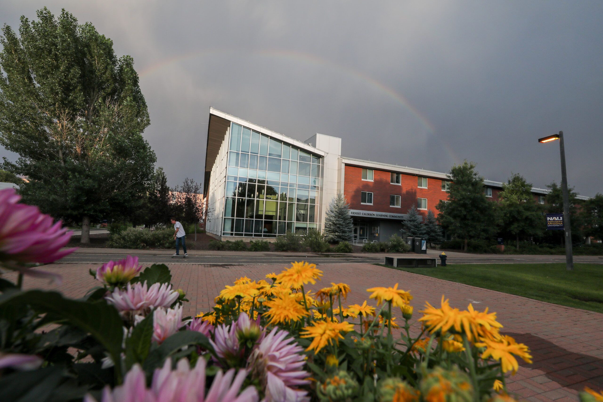 The outside of Calderon Hall, a residential space, surrounded by trees and flowers on the NAU campus.