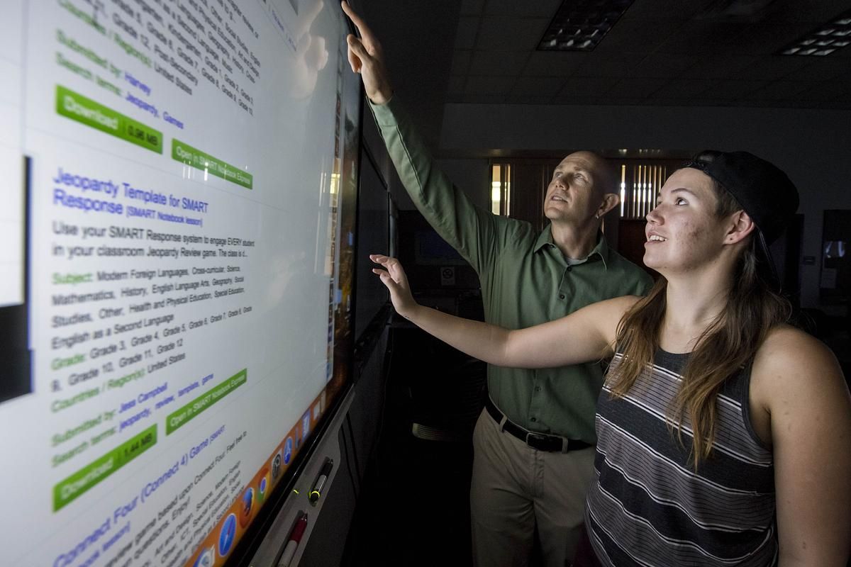 A professor and student work on a interactive white board.