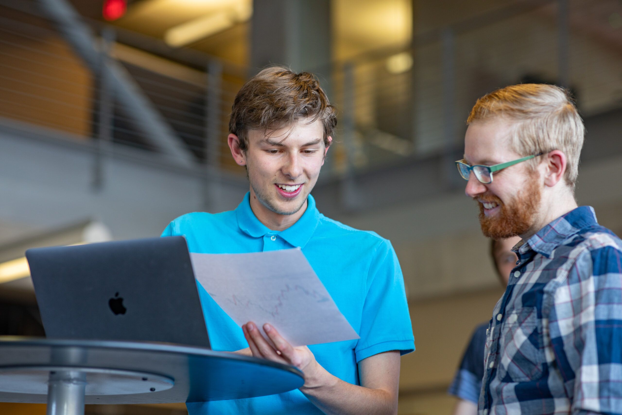 Two students looking at a report and a computer.