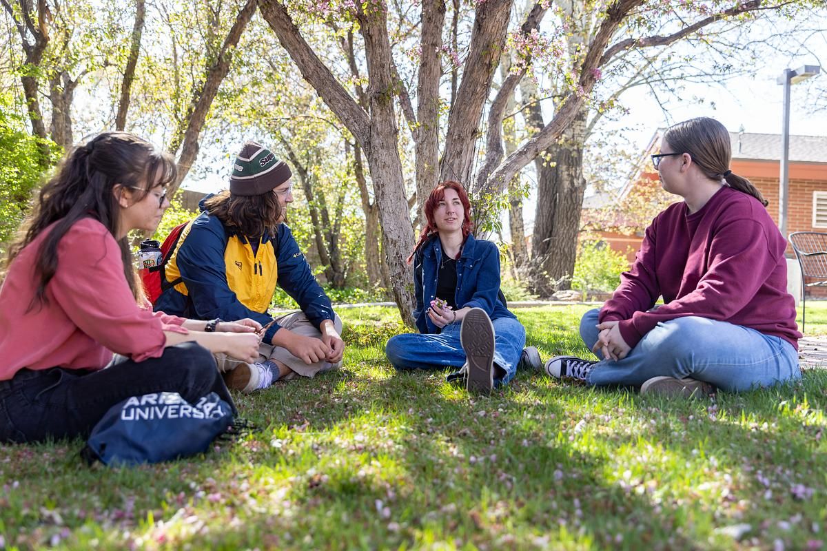 NAU students sit on a grassy field.