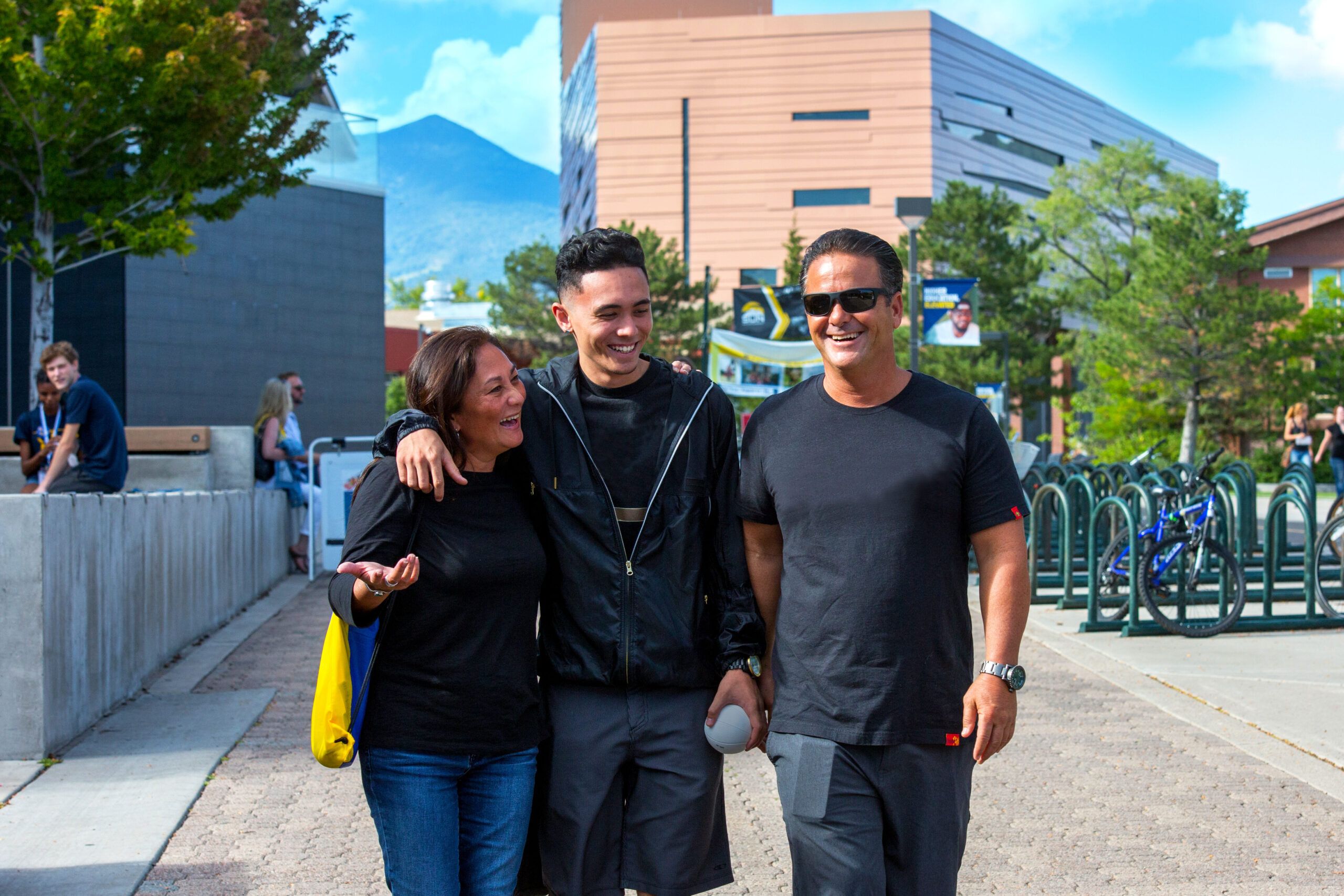 An NAU student smiles with his parents while walking through campus.