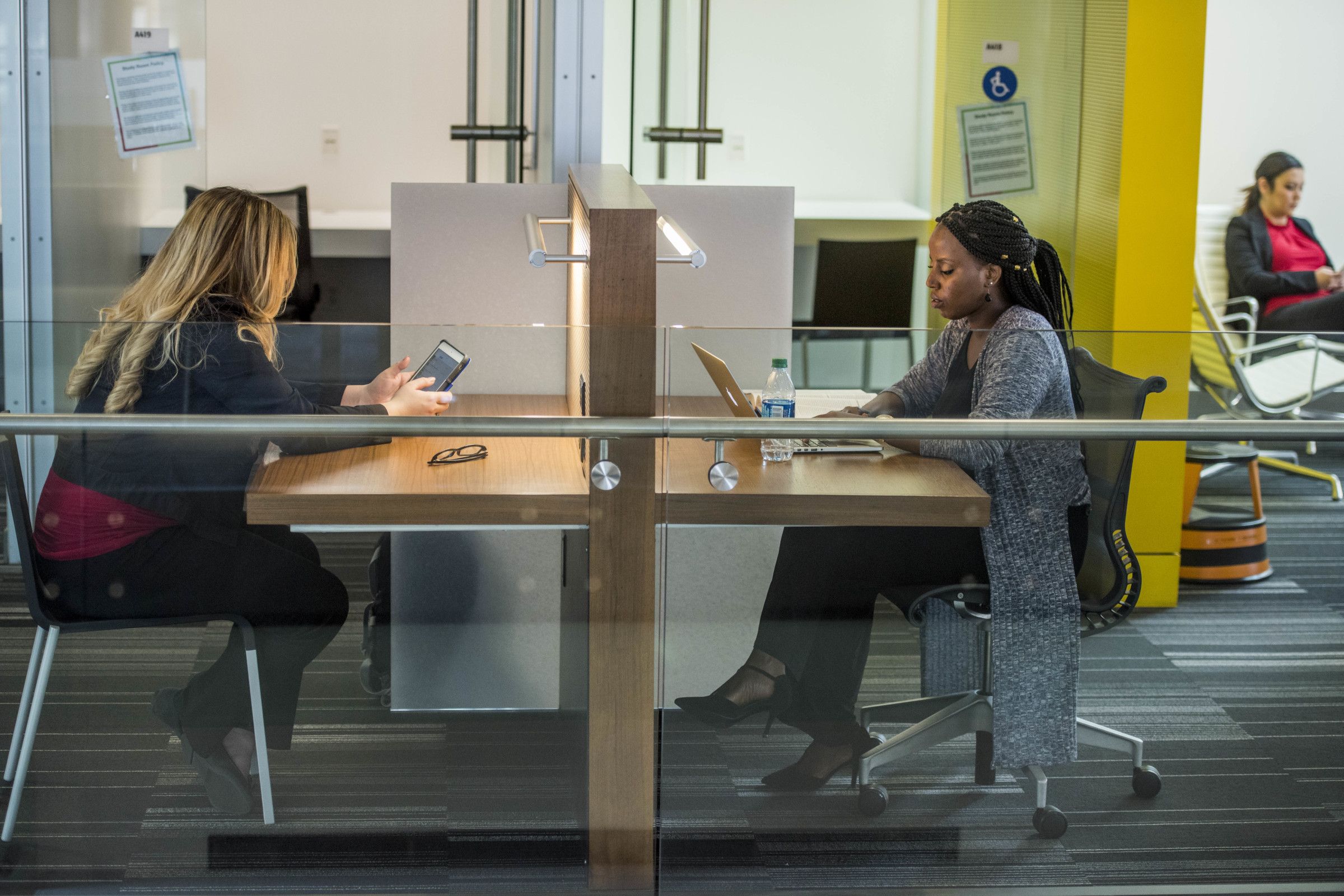 Two students sitting in cubicles working on computers and studying at the Phoenix Biomedical Core.