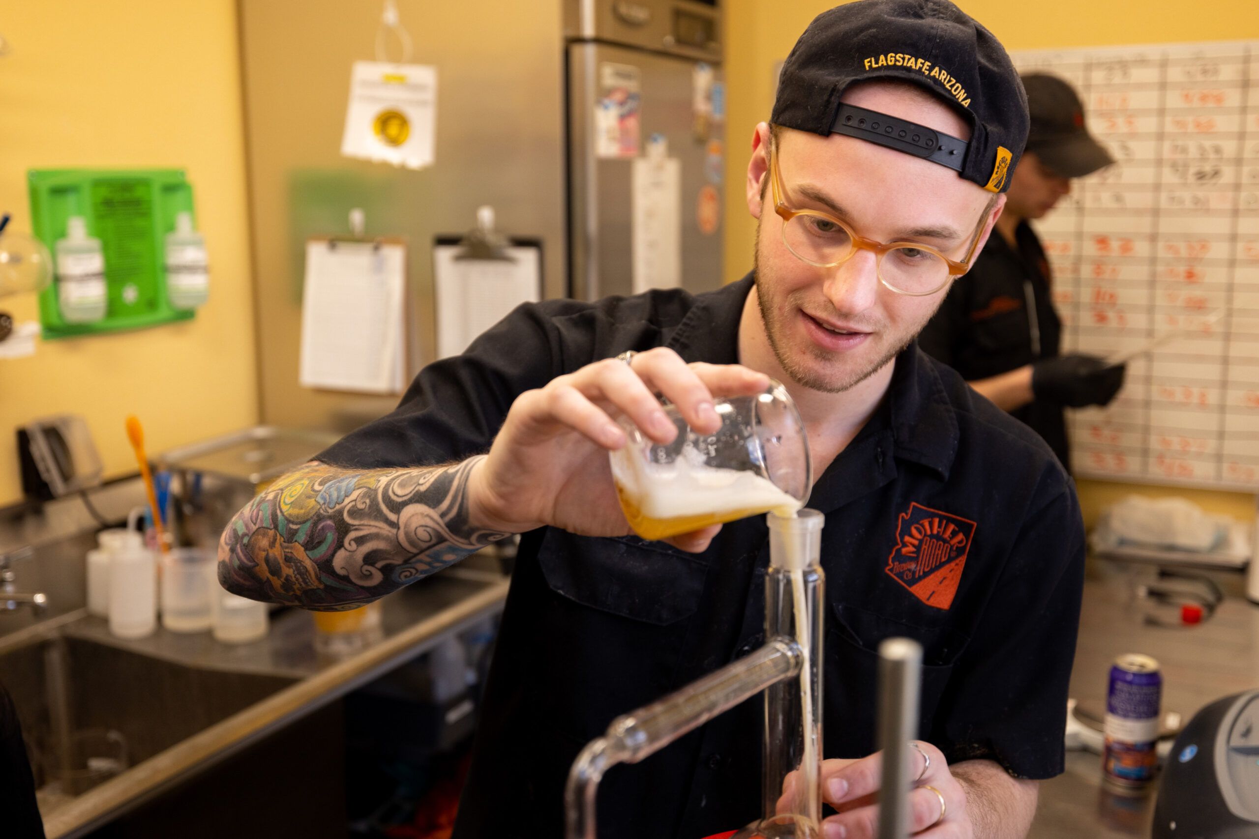 A brewer at Mother Road Brewing pours liquid into a measuring device.
