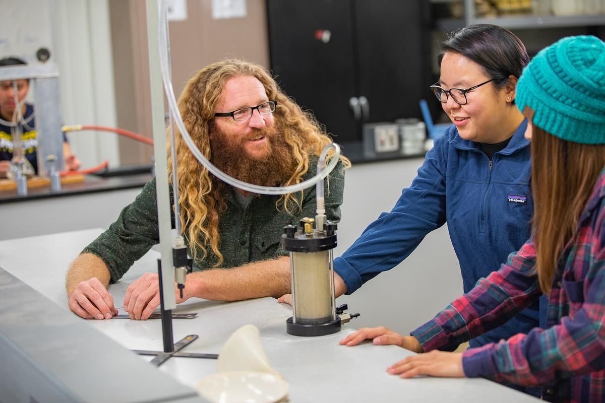 Students work with civil engineering equipment in a lab setting.