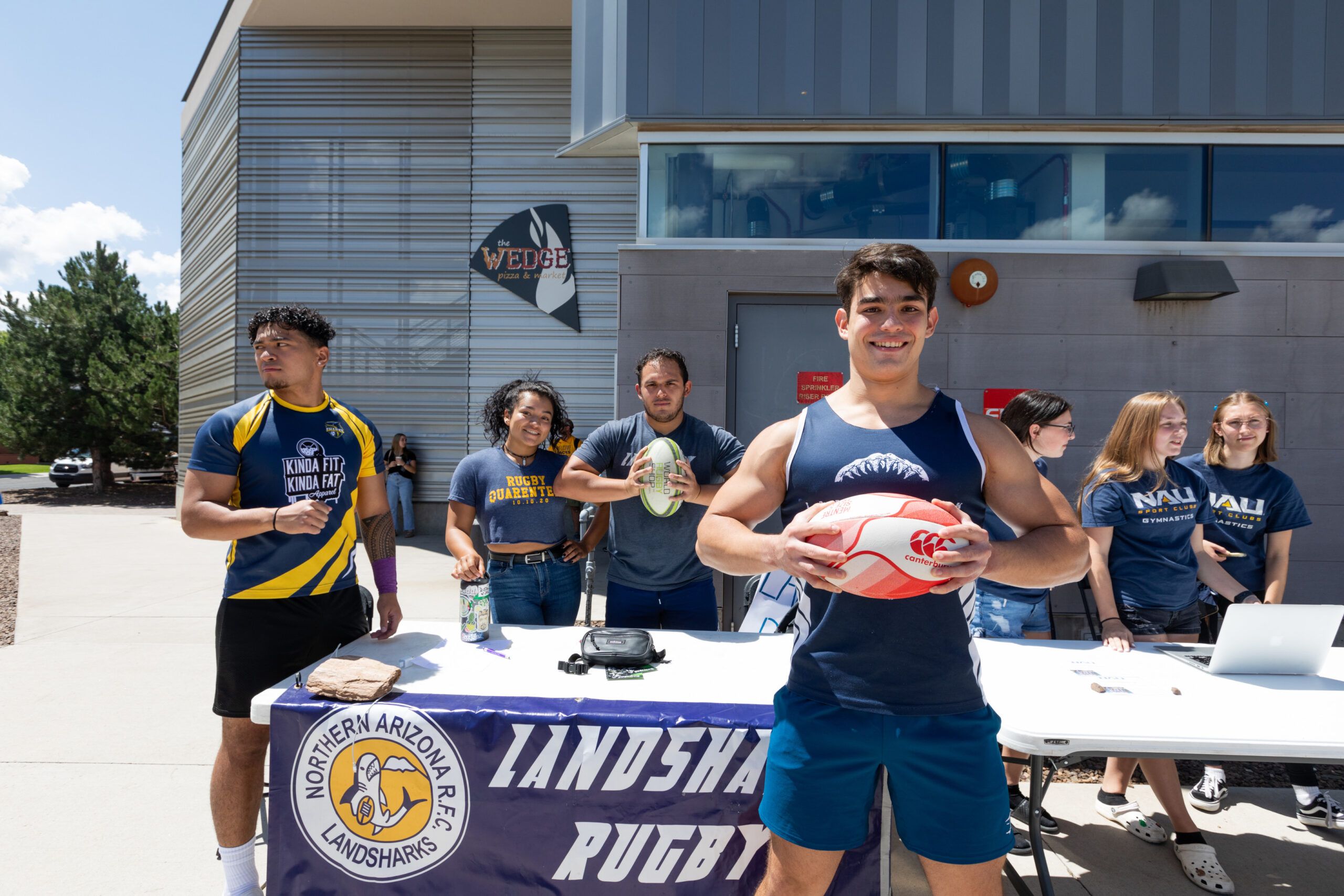 Several students standing around a booth advocating for their club at NAU's Club Fair.